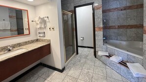 Ein modernes Badezimmer mit Marmorfliesen, einem großen Spiegel, einer Duschkabine und einer Badewanne.