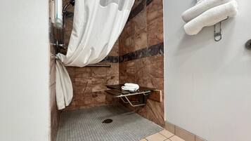 A shower area with a glass door, a towel rack, and a shelf unit.