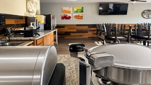 Ein Küchenbereich mit Grill aus Edelstahl, einer Kaffeemaschine und einem an der Wand befestigten Fernseher.