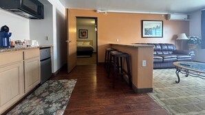A compact living space with a kitchenette, a dining area, and a seating area with a sofa and a coffee table. - FairBridge Inn & Suites Thermopolis (Thermopolis)