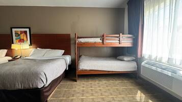 A hotel room with two beds, a bedside table with a lamp, a painting on the wall, and a window with curtains.