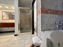 Un baño moderno con ducha envuelta en vidrio, una bañera amplia y suelo de mármol.