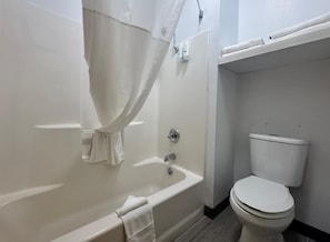 A bathroom with a bathtub, toilet, and a shower curtain.