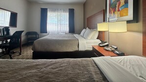Ein Hotelzimmer mit einem großen Bett, einem Schreibtisch mit Stuhl, einem Telefon und einem Gemälde an der Wand.