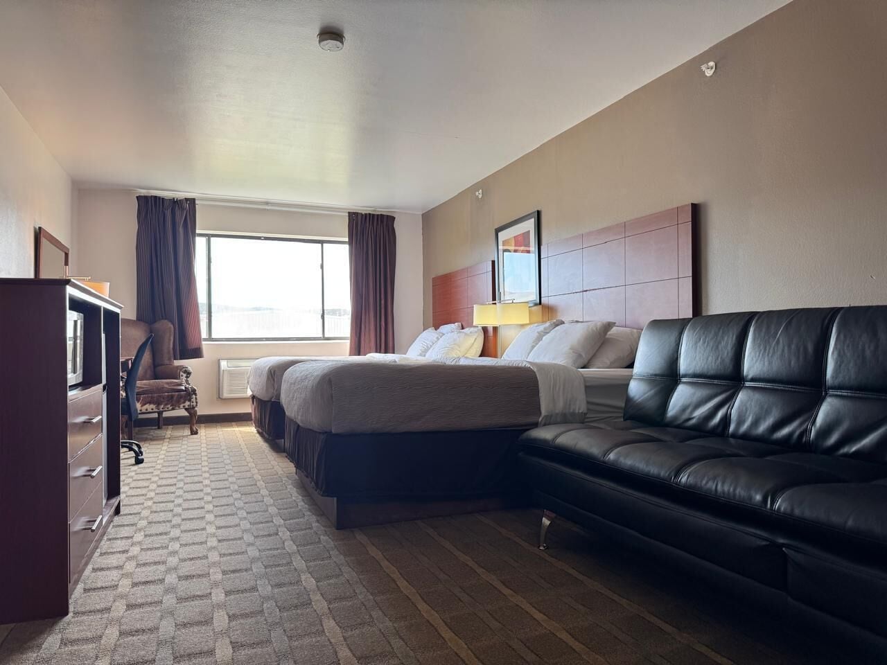 Ein Hotelzimmer mit Bett, Sofa, Schreibtisch und Stuhl.