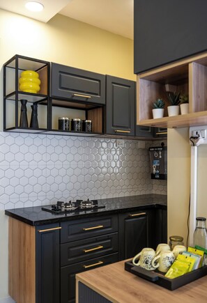 Une cuisine moderne avec des meubles de rangement noirs, un dosseret en carreaux hexagonaux et un plan de travail en bois.