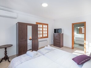 A bedroom with a bed, a dresser, a TV, and a bathroom visible through an open door. - Dofins Bahia Azul by Interhome (Llucmajor)