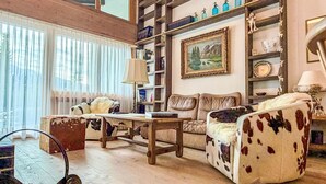 Ein gemütliches Wohnzimmer mit Holzboden, einer Couch, einem Couchtisch und einem Bücherregal.