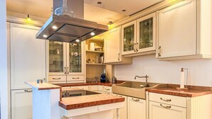 Eine Küche mit weißen Schränken, einer zentralen Kochinsel und einem eingebauten Backofen.