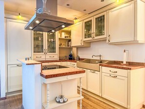 Eine Küche mit weißen Schränken, einer zentralen Kochinsel und einem eingebauten Backofen.