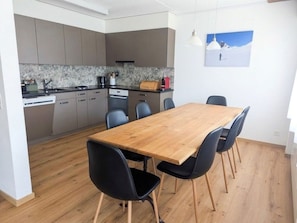 A modern kitchen with grey cabinets, a wooden dining table, and black chairs. - Val Signina 3-28 by Interhome (Laax)