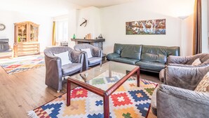 A living room with a sofa, armchairs, a coffee table, a cabinet, and a painting on the wall. - Val Signina 4-8 by Interhome (Laax)