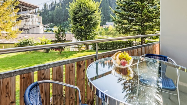 A balcony with a glass table, blue chairs, and a bowl of fruit. - Val Signina 4-8 by Interhome (Laax)