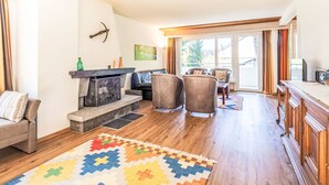 A living room with a fireplace, two armchairs, a sofa, and a colorful rug. - Val Signina 4-8 by Interhome (Laax)