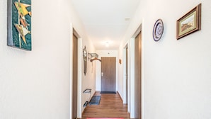 A hallway with a wooden floor, a red rug, and a door at the end. - Val Signina 4-8 by Interhome (Laax)