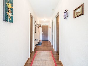 Ein Korridor mit Holzboden, einem roten Teppich und einer Tür am Ende.