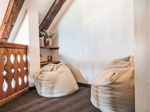 A corner of a room with a wooden slat partition, a small shelf with decorative items, and two bean bags. - Val Signina 8-18 by Interhome (Laax)