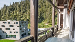 En balkong med utsikt över en modern byggnad och ett skogsområde.