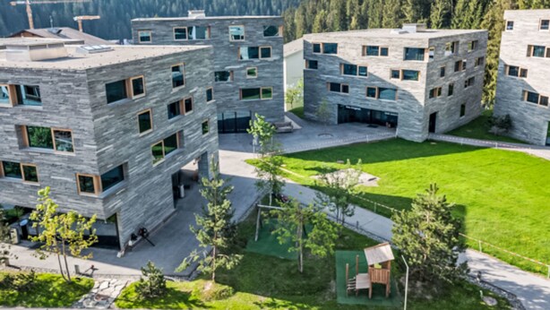 En modern byggnad med en fasad av sten, många fönster och en grön gräsmatta framför.