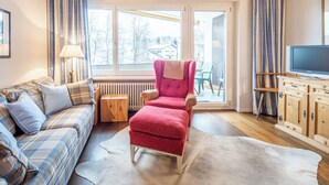 A cozy living room with a plaid sofa, a red armchair, a wooden cabinet, and a television. - Quadra B223 by Interhome (Flims)