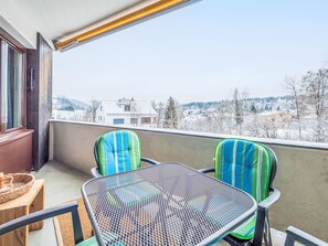 A balcony with two chairs and a table, overlooking a snowy landscape with buildings. - Quadra Apt. B223 by Interhome (Flims)