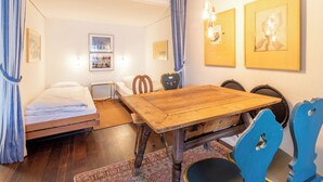A room with a bed, a wooden dining table, chairs, a rug, and wall-mounted artwork. - Quadra B223 by Interhome (Flims)