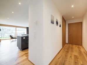 Un interno moderno con pavimento in legno, angolo cottura e un'ampia finestra con vista.
