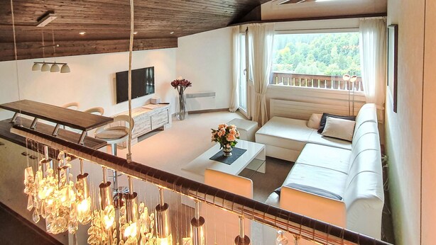 Ein modernes Interieur mit Essbereich, Sofa und einem Balkon mit Aussicht.