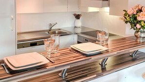 Eine moderne Küche mit Holzboden, Pendelleuchten, einem Edelstahlherd und einer Holz Arbeitsplatte.