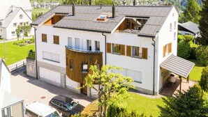 Een modern huis met twee verdiepingen, een garage, een balkon en uitzicht op het omliggende landschap.