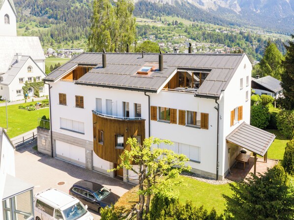 Une maison moderne à deux étages, dotée d’un garage, d’un balcon et offrant une vue sur le paysage environnant.