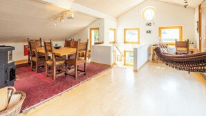 Een ruime loft met een eethoek, een hangmat en uitzicht op de omgeving.