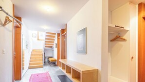 Een hal met een houten bankje, een rode kleed en een trap naar een andere kamer.