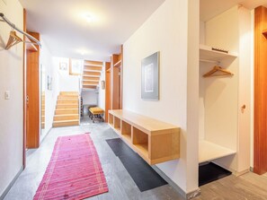 Ein Flur mit einer hölzernen Bank, einem roten Teppich und einer Treppe, die in ein anderes Zimmer führt.
