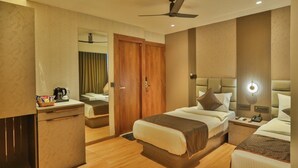 Quarto de hotel com cama, mesa de cabeceira, luminária e espelho.