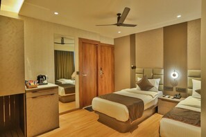 A hotel room with a bed, bedside table, lamp, and a mirror. - emersion residency (PUNE)