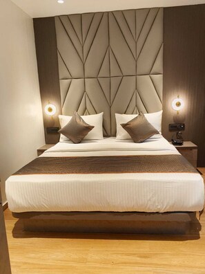 A large bed with a geometric headboard, two bedside lamps, and a telephone on the nightstand. - emersion residency (PUNE)