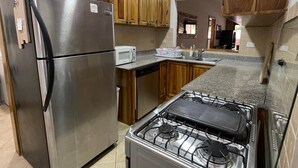 Una cucina con elettrodomestici in acciaio inossidabile, mobili in legno, un forno a microonde e un piano cottura a gas.