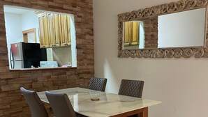 Zona pranzo con tavolo in marmo, sedie imbottite, parete decorata con pietra e un grande specchio.