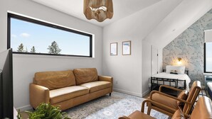 Uma sala de estar moderna com uma grande janela, um sofá, um espaço de refeições e uma cama com um design de papel de parede exclusivo.