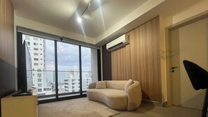 A modern living room with a sofa, a TV, a large window, and an air conditioning unit. - Modern Apartments at the Hub City views (Panamá)