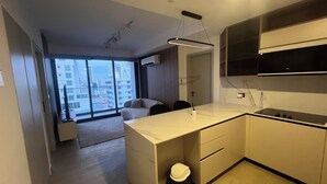 A modern kitchen with a large window, a dining area with a sofa, and a view of the cityscape. - Modern Apartments at the Hub City views (Panamá)