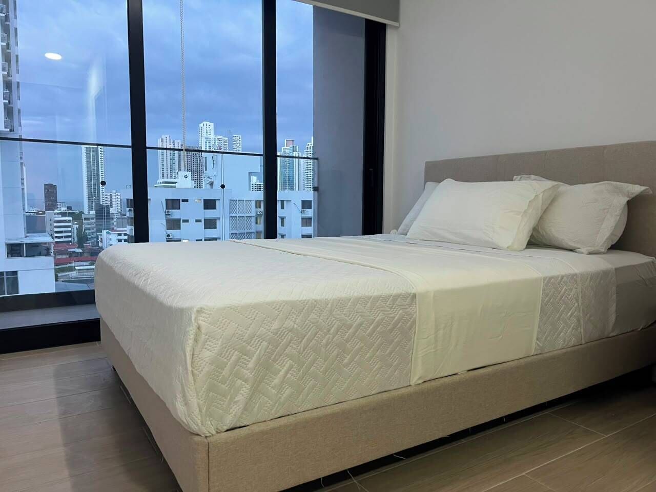 Un dormitorio con una cama, un ventanal grande y vistas a la ciudad.