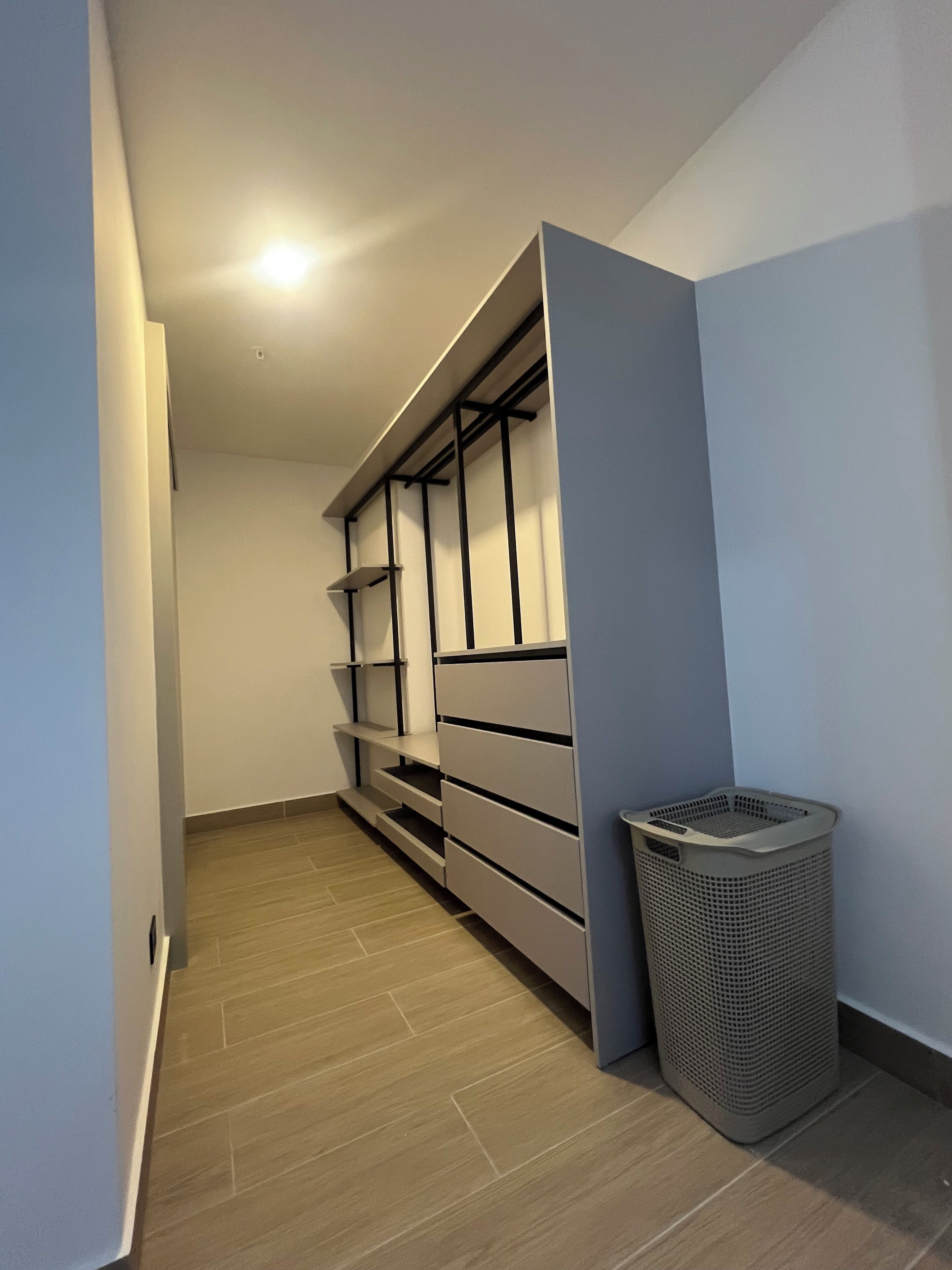 A narrow hallway with a built-in storage unit and a trash bin.