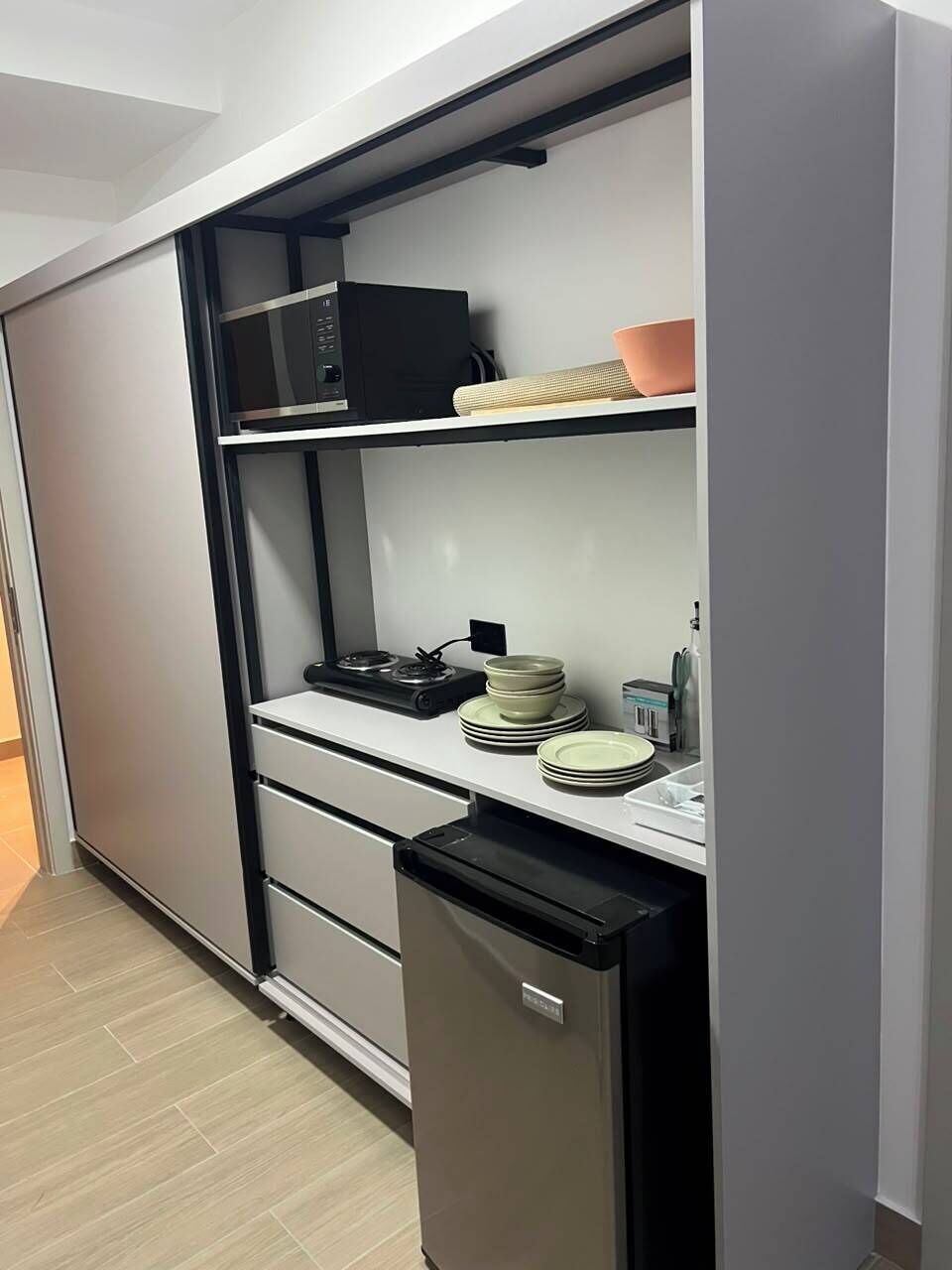 Une cuisine compacte équipée d’un four à micro-ondes, d’une cuisinière et d’une pile d’assiettes.