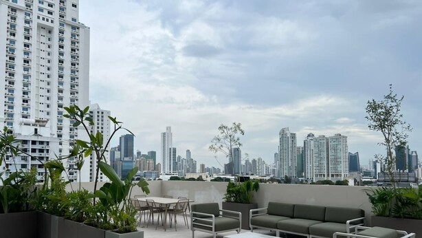A rooftop terrace with outdoor furniture, potted plants, and a city skyline view. - Modern Apartments at the Hub City views (Panamá)