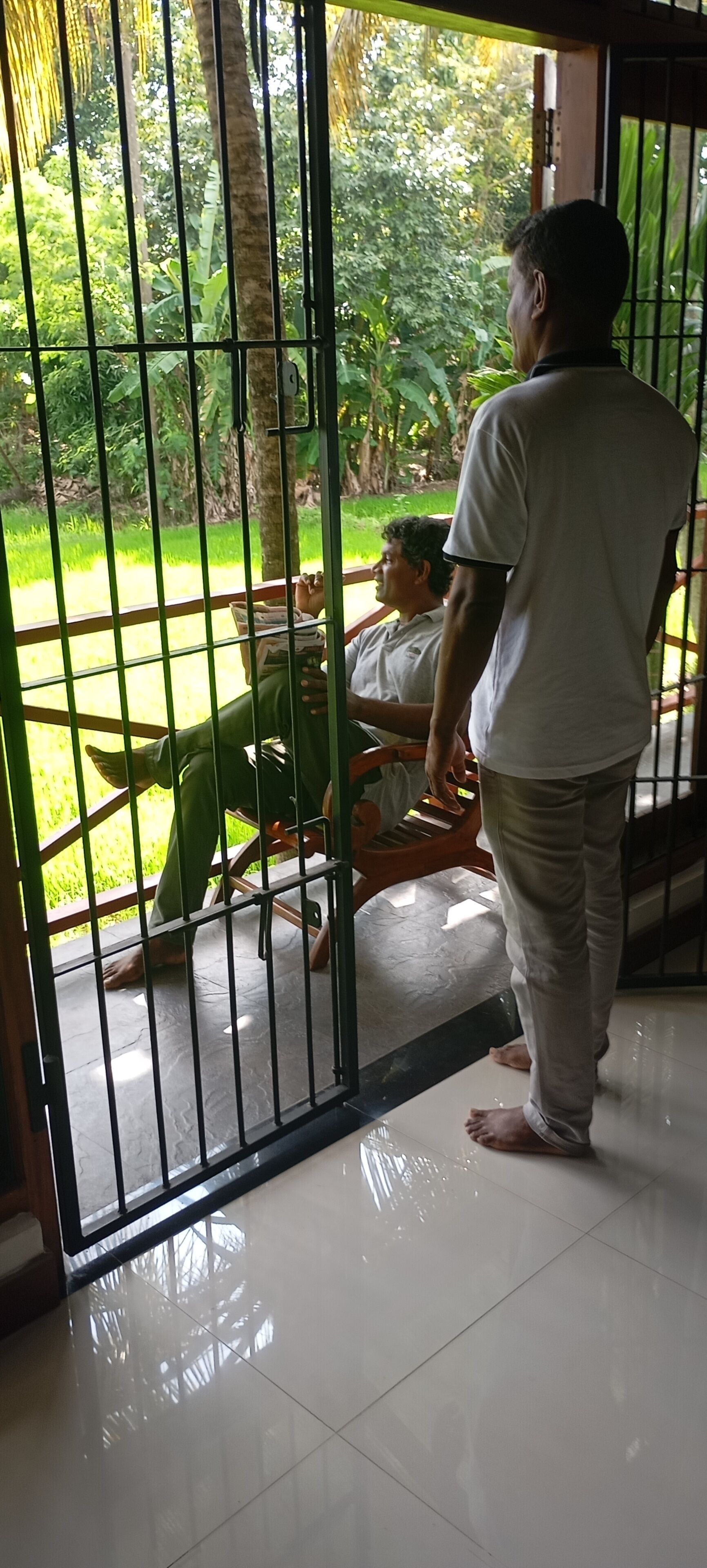 A man standing in a doorway with a metal gate, looking outside.