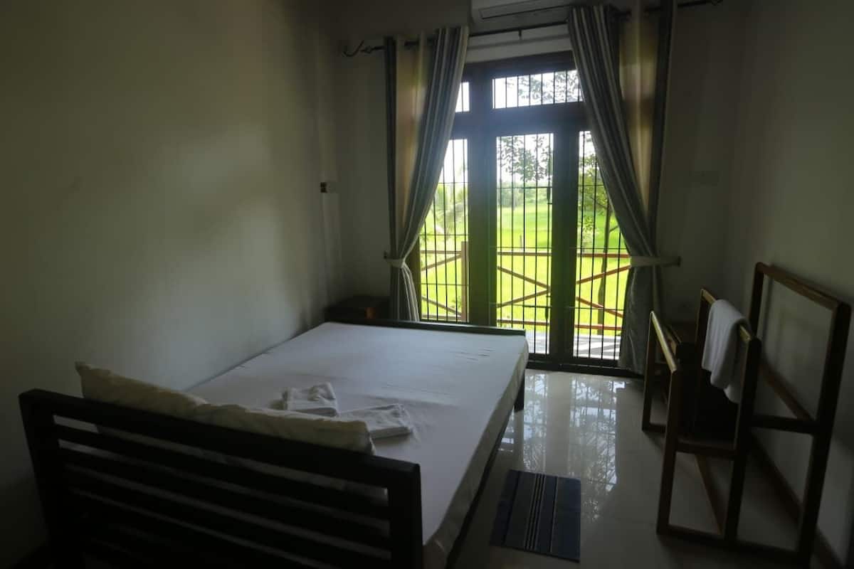 A bedroom with a bed, a chair, a desk, and a window with curtains.