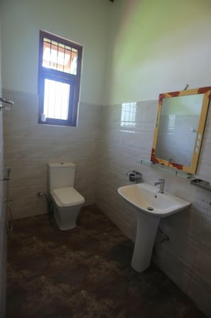 A bathroom with a toilet, sink, and a mirror with a decorative frame.