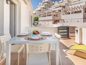 A white outdoor dining area with a table set for two, surrounded by white chairs. - Sunlight by Interhome (Peñiscola)